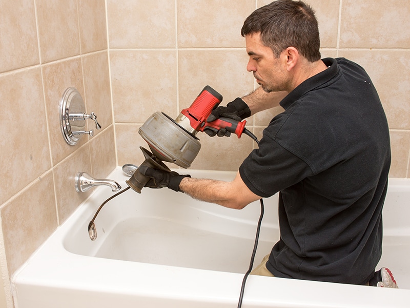a plumber cleaning a bathroom drain