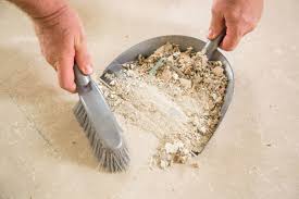 cleaning up debris and dust from a bathroom with dustpan and broom